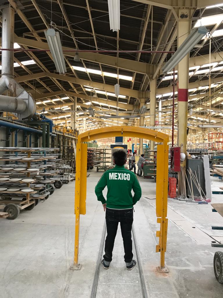 A person wearing a green jacket stands with their back to the camera and is looking at a large ceramics factory