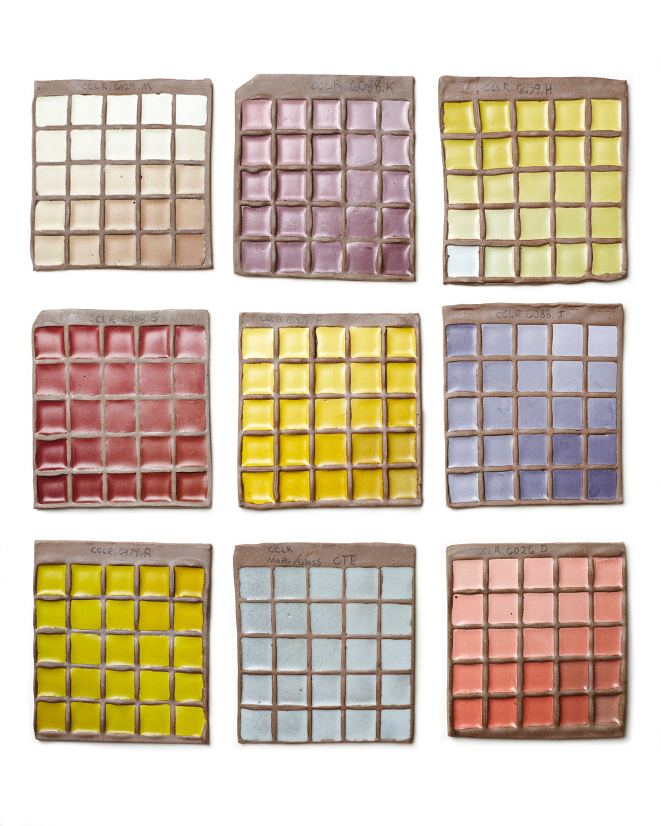 A lineup of ceramic palettes with square glaze swatches all over them.