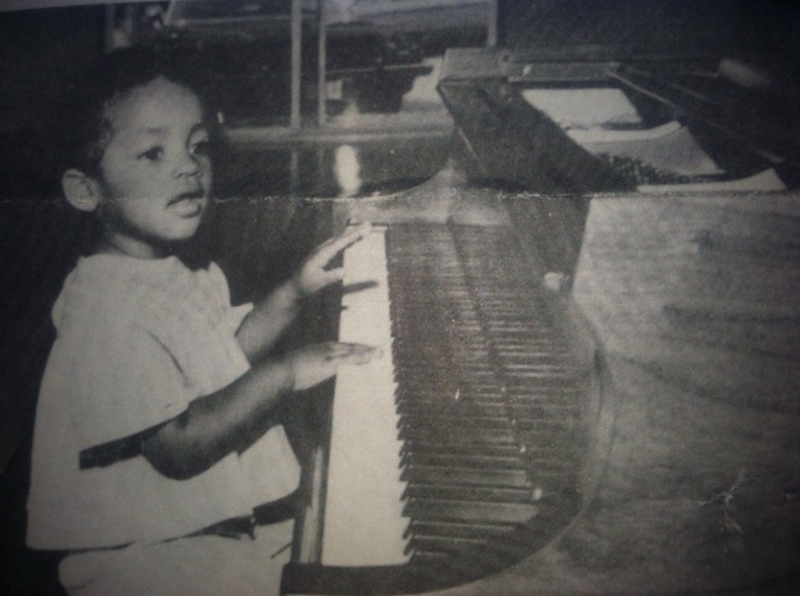 a black and white photo of a young child playing a piano