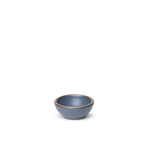 A tiny rounded ceramic bowl in a cool medium blue color featuring iron speckles and an unglazed rim