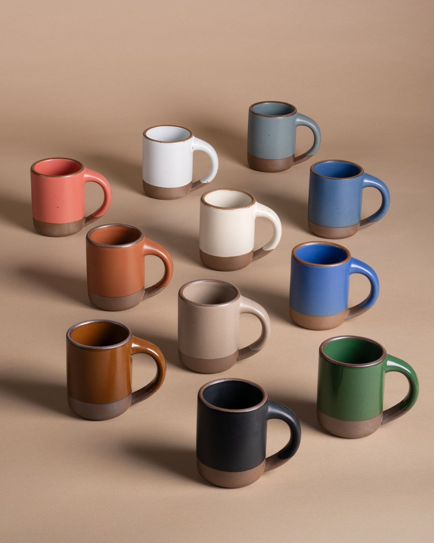 A lineup of ceramic mugs in a rainbow of different colors