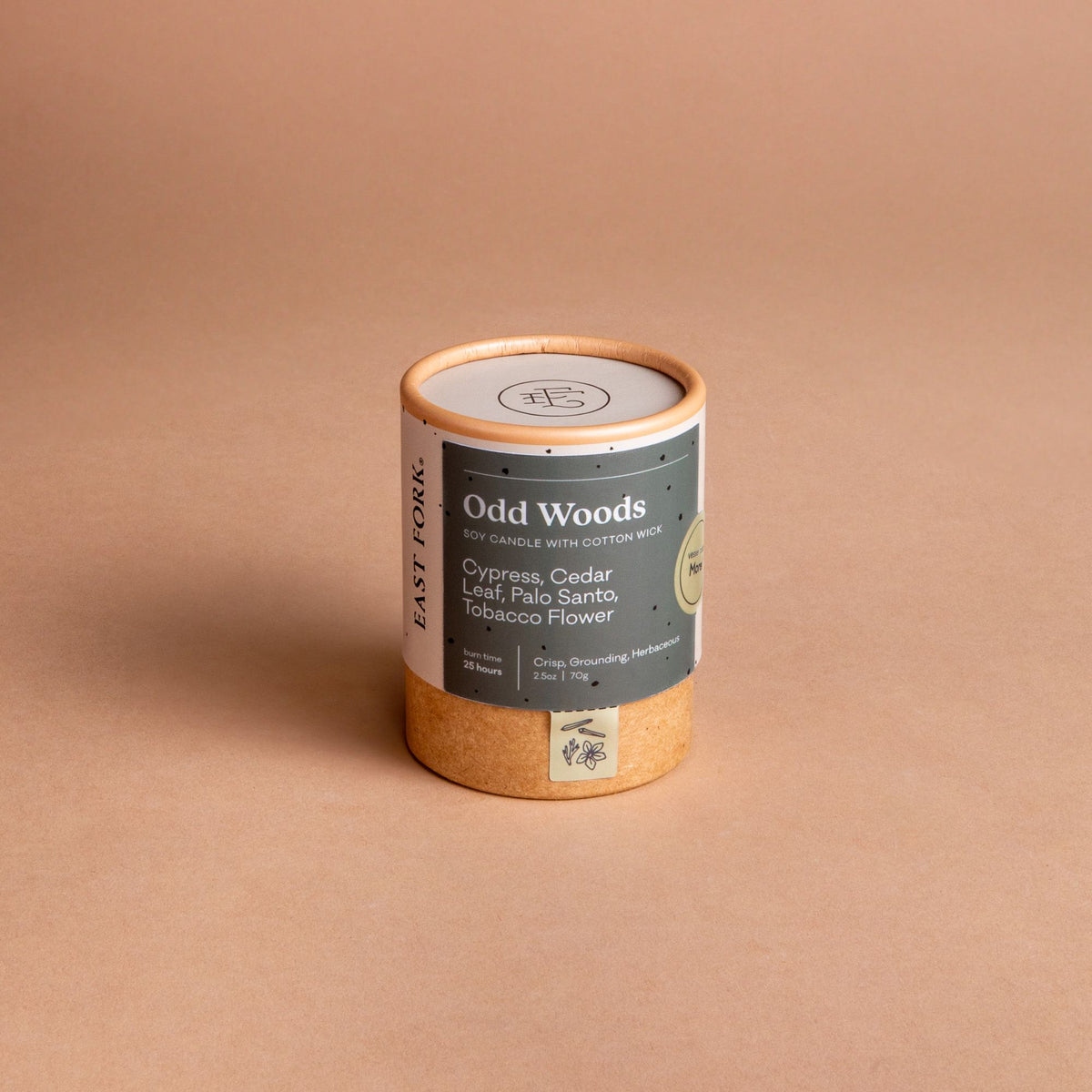 Small cardboard packaging tube with a candle inside with branding on it that says 'Odd Woods'