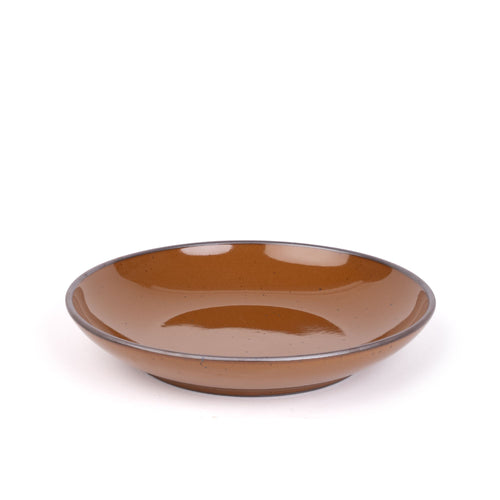 A large ceramic plate with a curved bowl edge in a glossy caramel brown color featuring iron speckles and an unglazed rim.