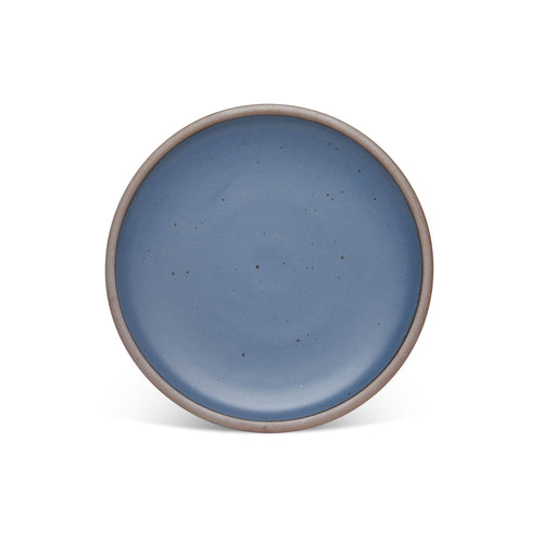 A dinner sized ceramic plate in a cool, medium blue color featuring iron speckles and an unglazed rim.