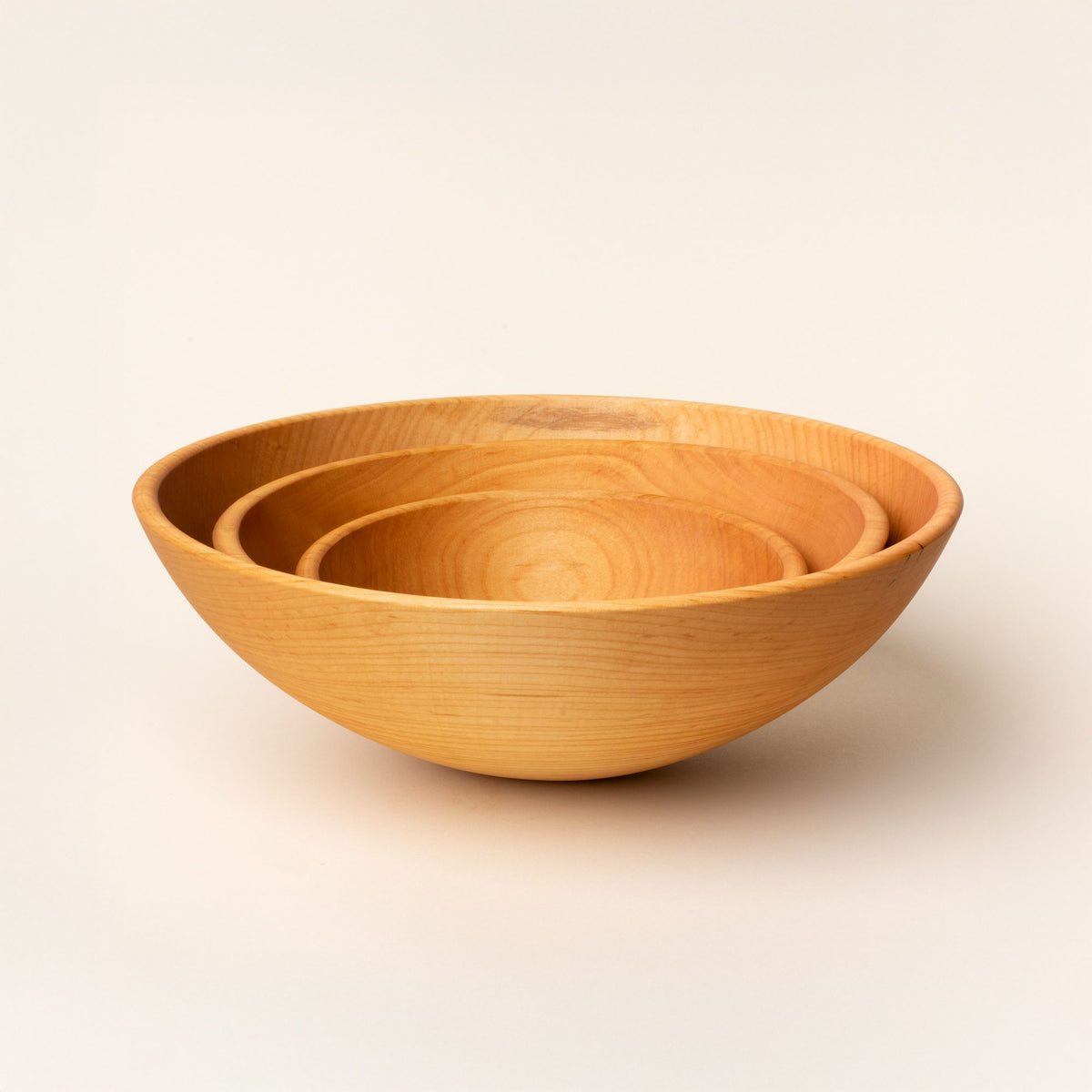 3 round maple wood bowls nesting together in small, medium, and large sizes.