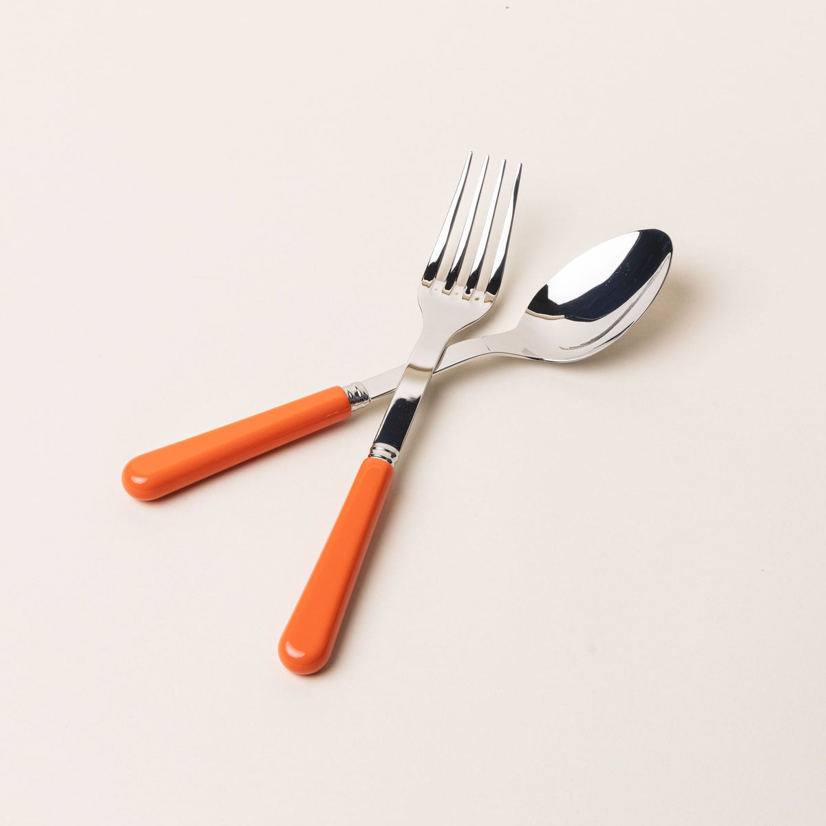 A serving size spoon and fork in a shiny steel with a bold orange handle