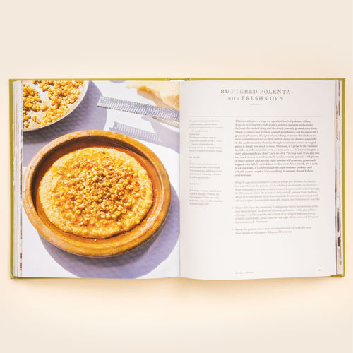 Open cookbook showing a buttered polenta with fresh corn recipe, with a photo of a wooden bowl filled with polenta topped with corn.