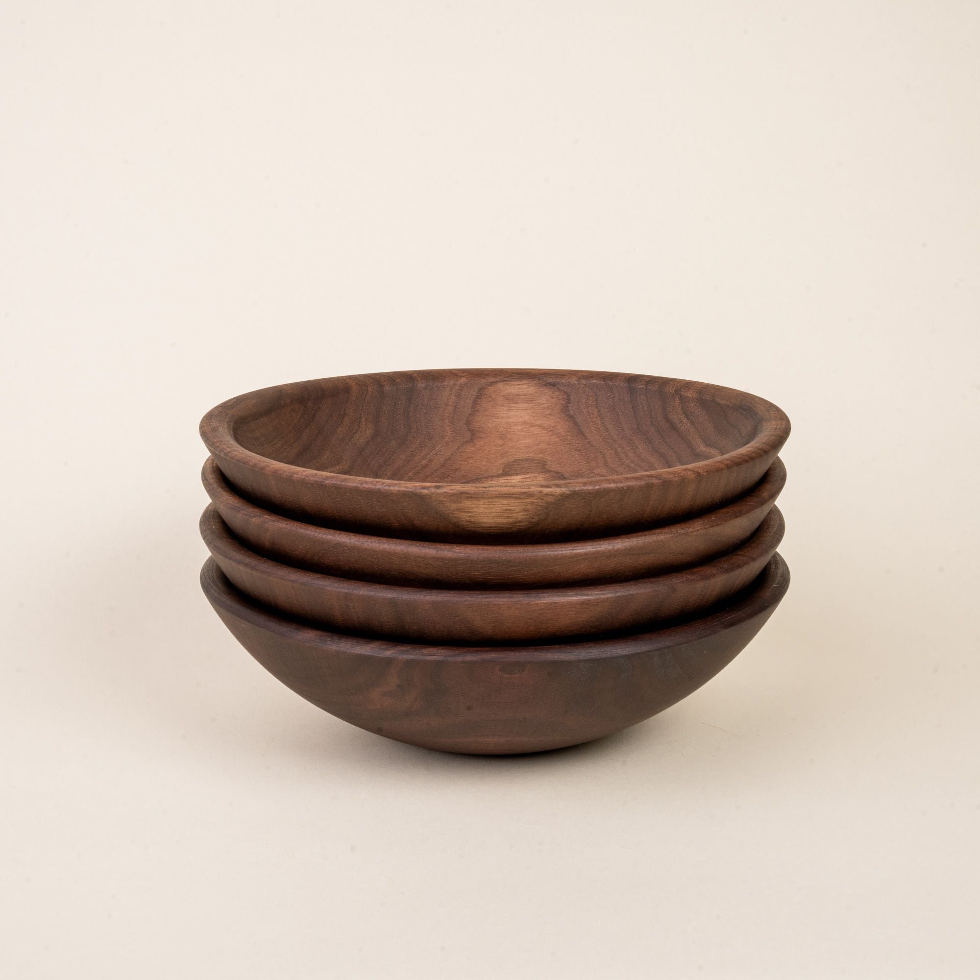 A stack of 4 small walnut wood bowls
