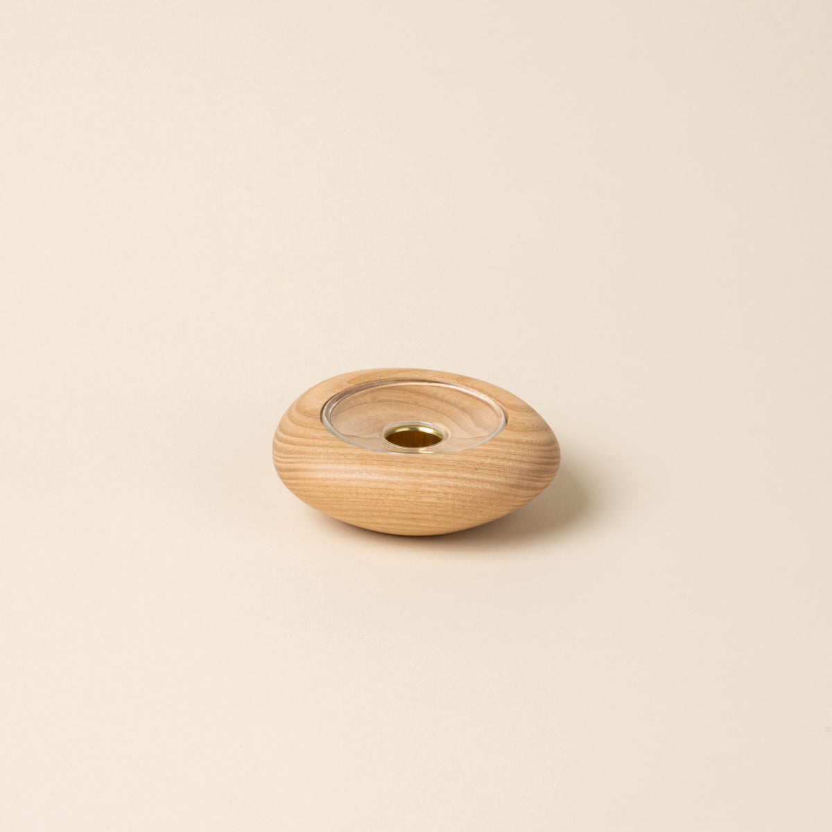 Small round light wood candle holder with visible grain and a glass insert in the center, displayed against a neutral background.