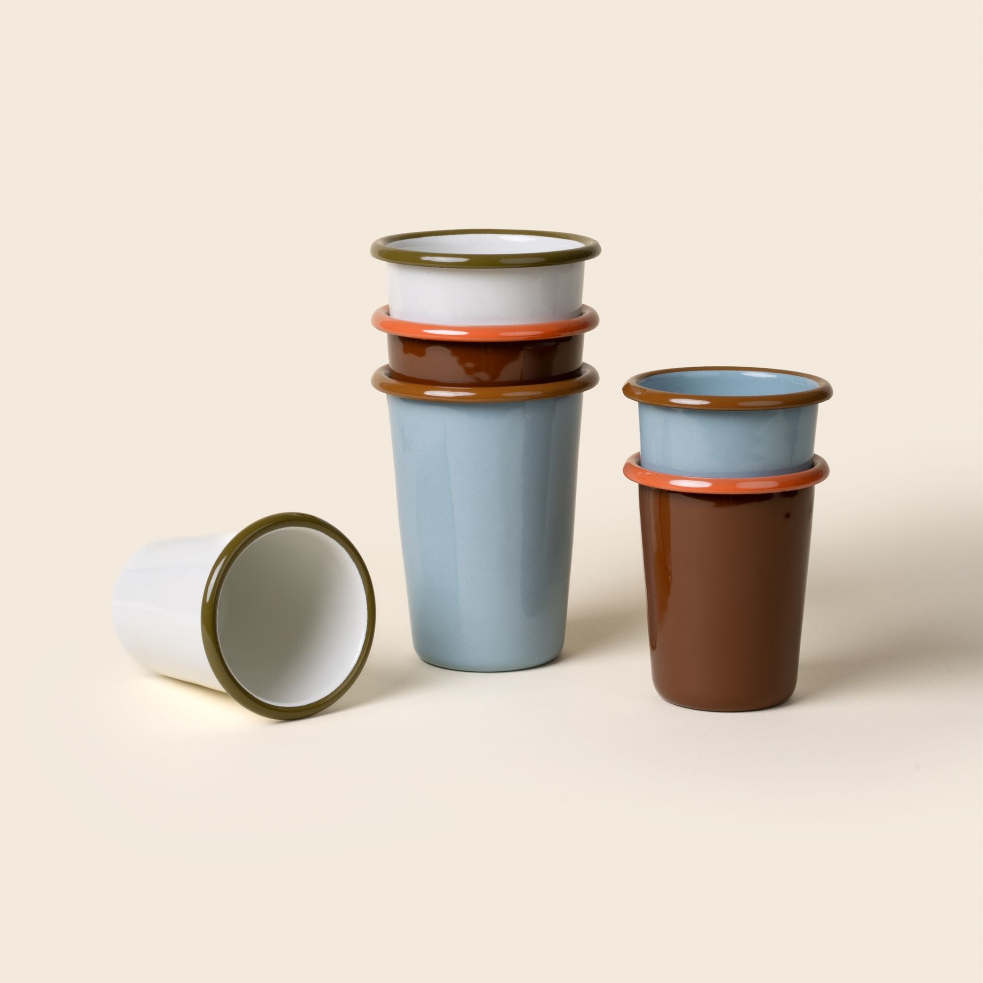 Stacks of short and tall enamel tumblers in robin's egg blue, white, and red-brown colors