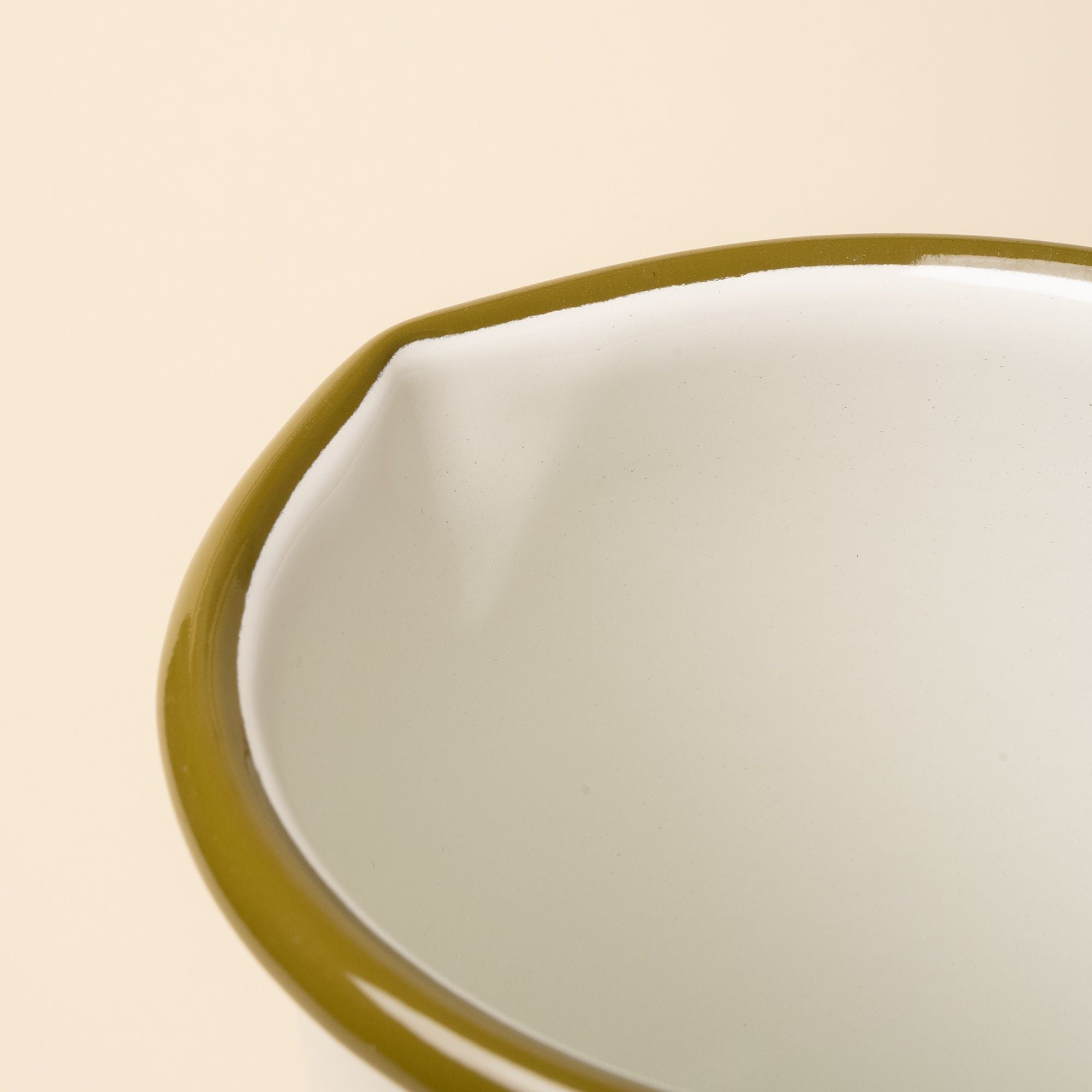 A closeup of the spout of an enamel pitcher.