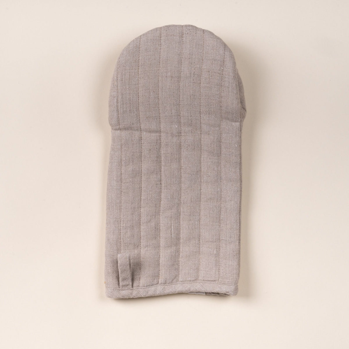 Natural color linen oven mitt with stitched channels and a small hanging loop, laid flat on a light background.