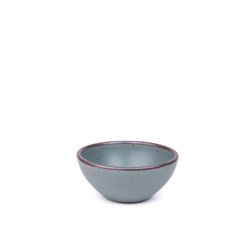 A small dessert sized rounded ceramic bowl in a blue-grey color featuring an unglazed rim