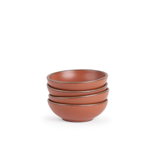 A stack of 4 small shallow ceramic bowls in a cool burnt terracotta color featuring iron speckles and an unglazed rim