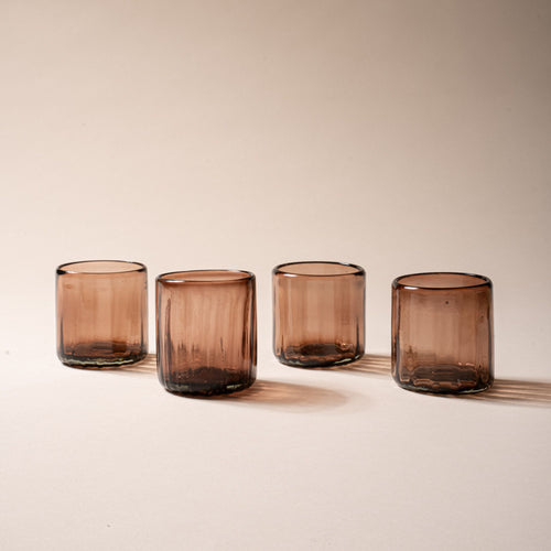 Four amber-brown textured glass tumblers with vertical ridges against a neutral background.