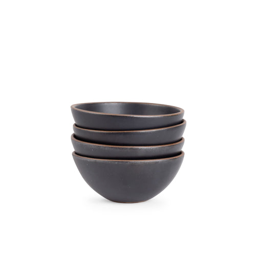 A stack of 4 medium rounded ceramic bowls in a graphite black color featuring iron speckles and an unglazed rim