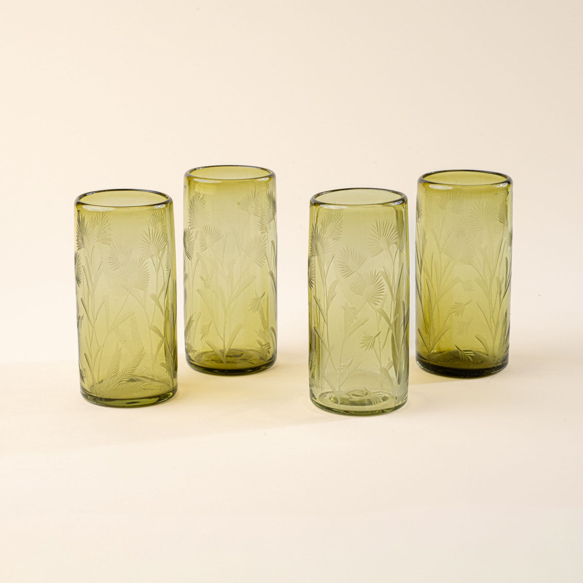 Four olive cylindrical glasses with delicate etched floral pattern, standing upright on a neutral background.