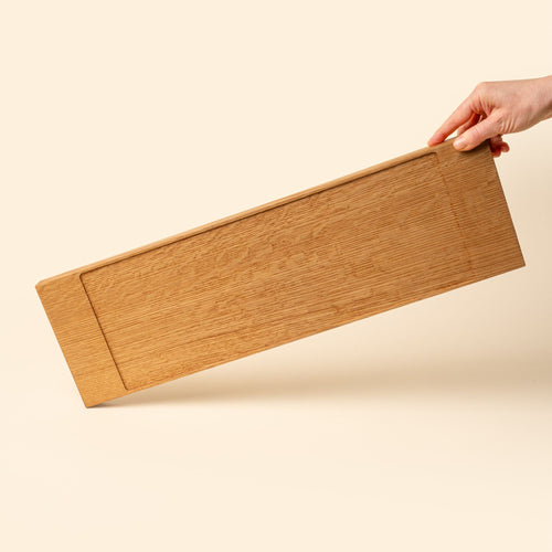 A narrow rectangle of light brown wood with a vertical groove at either end