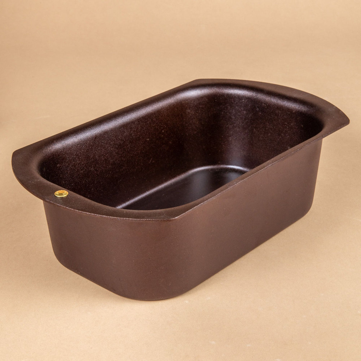 A black metal loaf pan with rounded corners and a wide flat lip