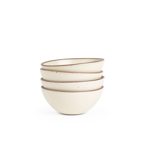 A stack of 4 medium rounded ceramic bowls in a warm, tan-toned, off-white color featuring iron speckles and an unglazed rim