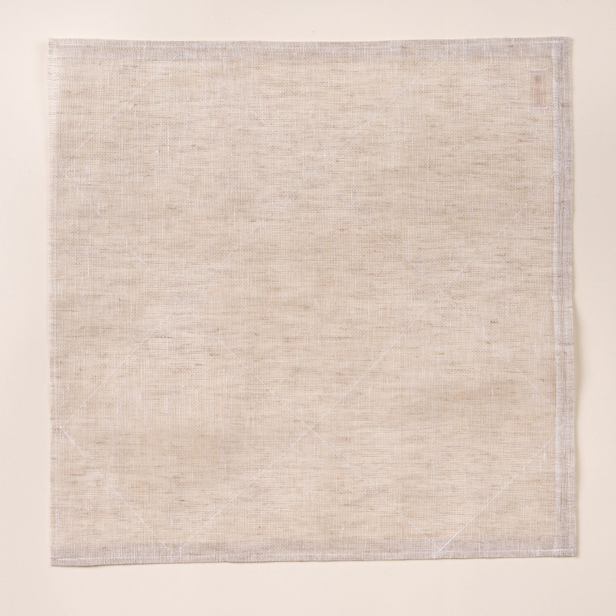 Square natural linen cleaning cloth laid flat on a light background, showing a subtle woven texture and stitched edges.