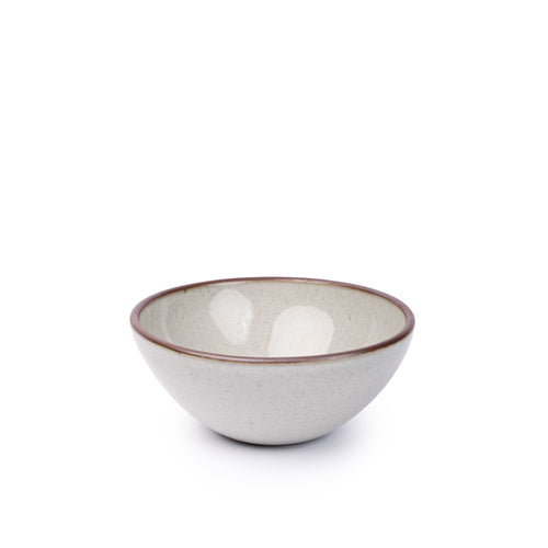 A medium rounded ceramic bowl in a reflective icy off-white color featuring iron speckles and an unglazed rim
