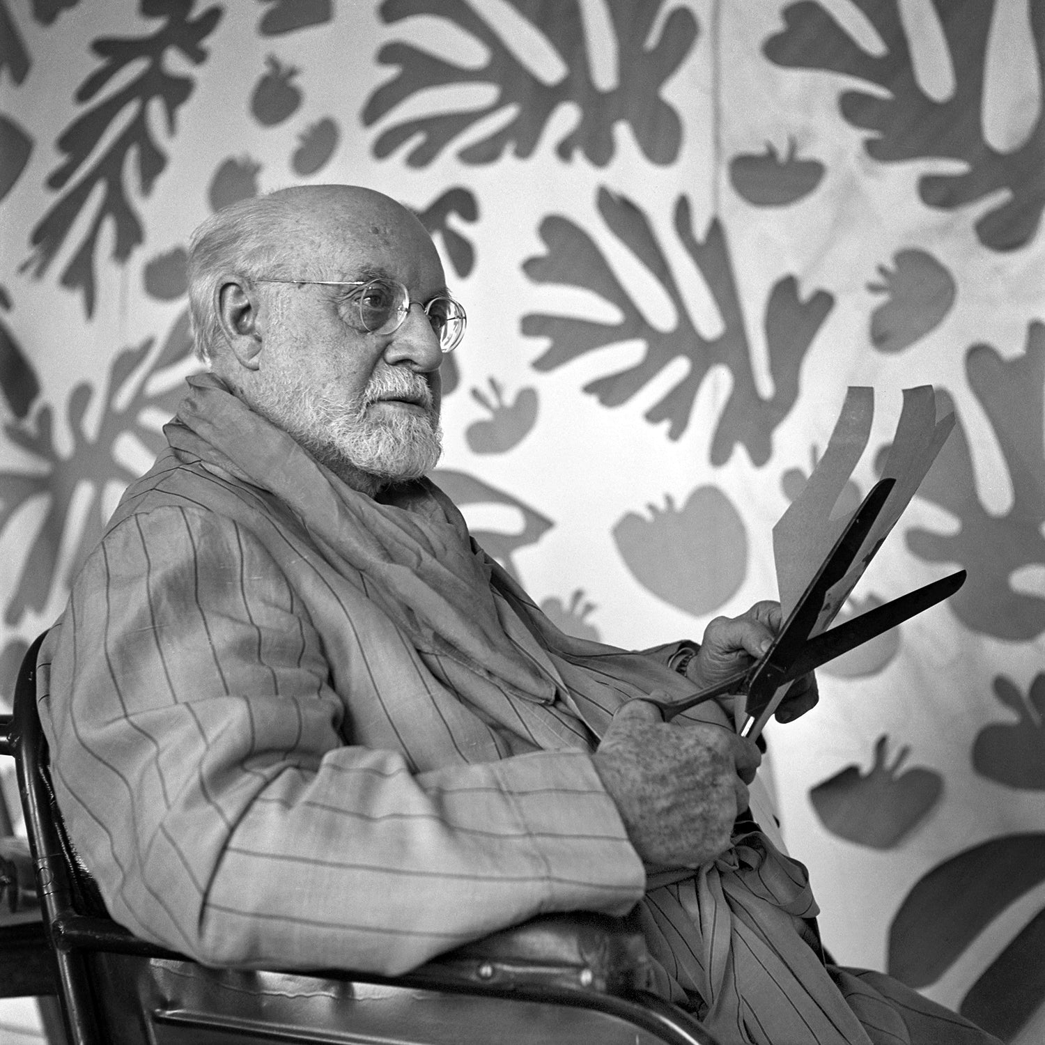 Henri Matisse in his studio holding scissors