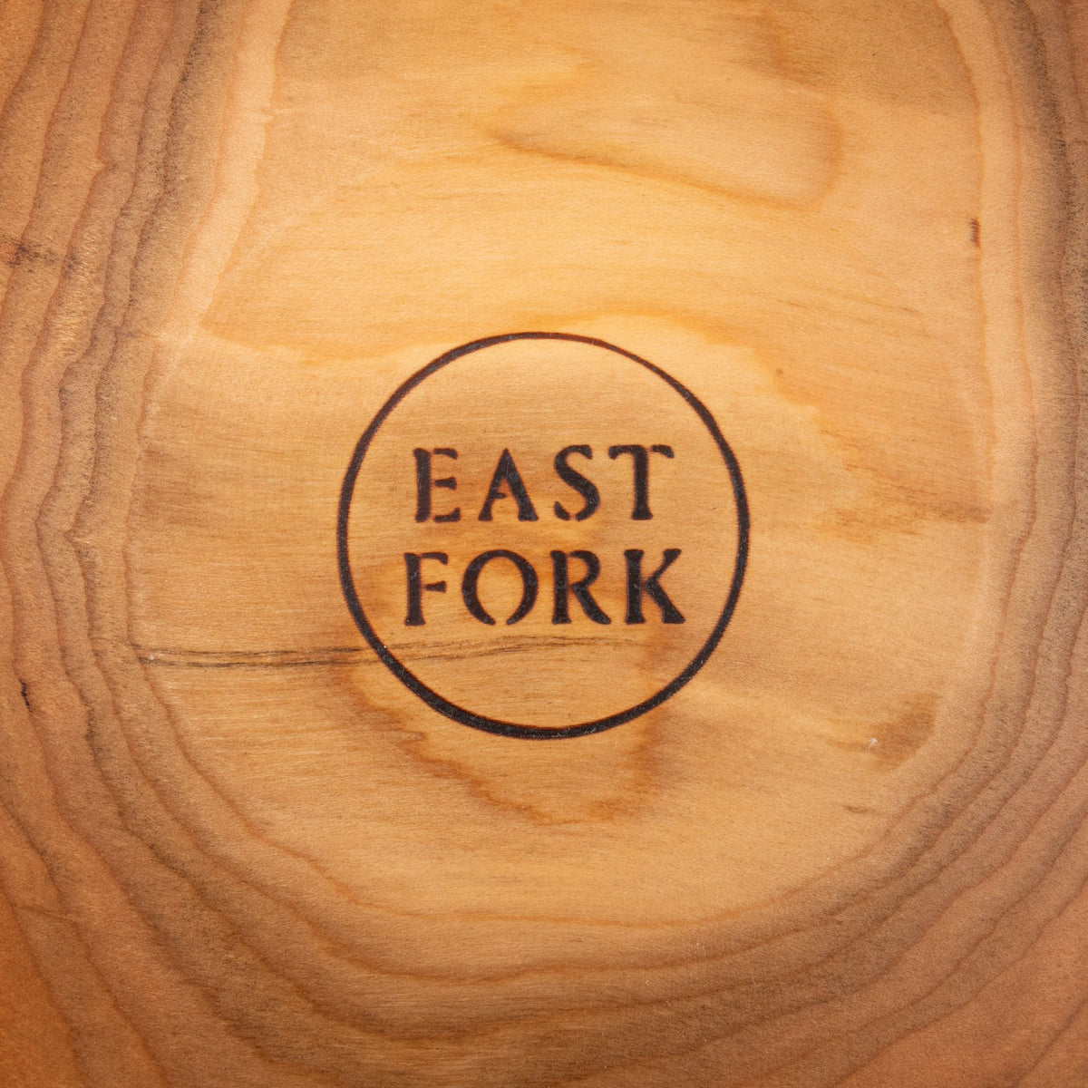 A close up of an East Fork stamp on the bottom of a cherry wood bowl