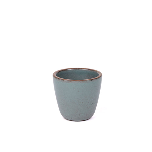 A short cup that tapers out to get wider at the top in a blue-grey color featuring iron speckles