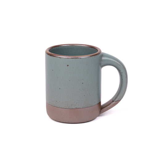 A big sized ceramic mug with handle in a blue-grey glaze featuring iron speckles and unglazed rim and bottom base.