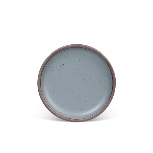 A medium sized ceramic plate in a blue-grey color with iron speckles and an unglazed rim.