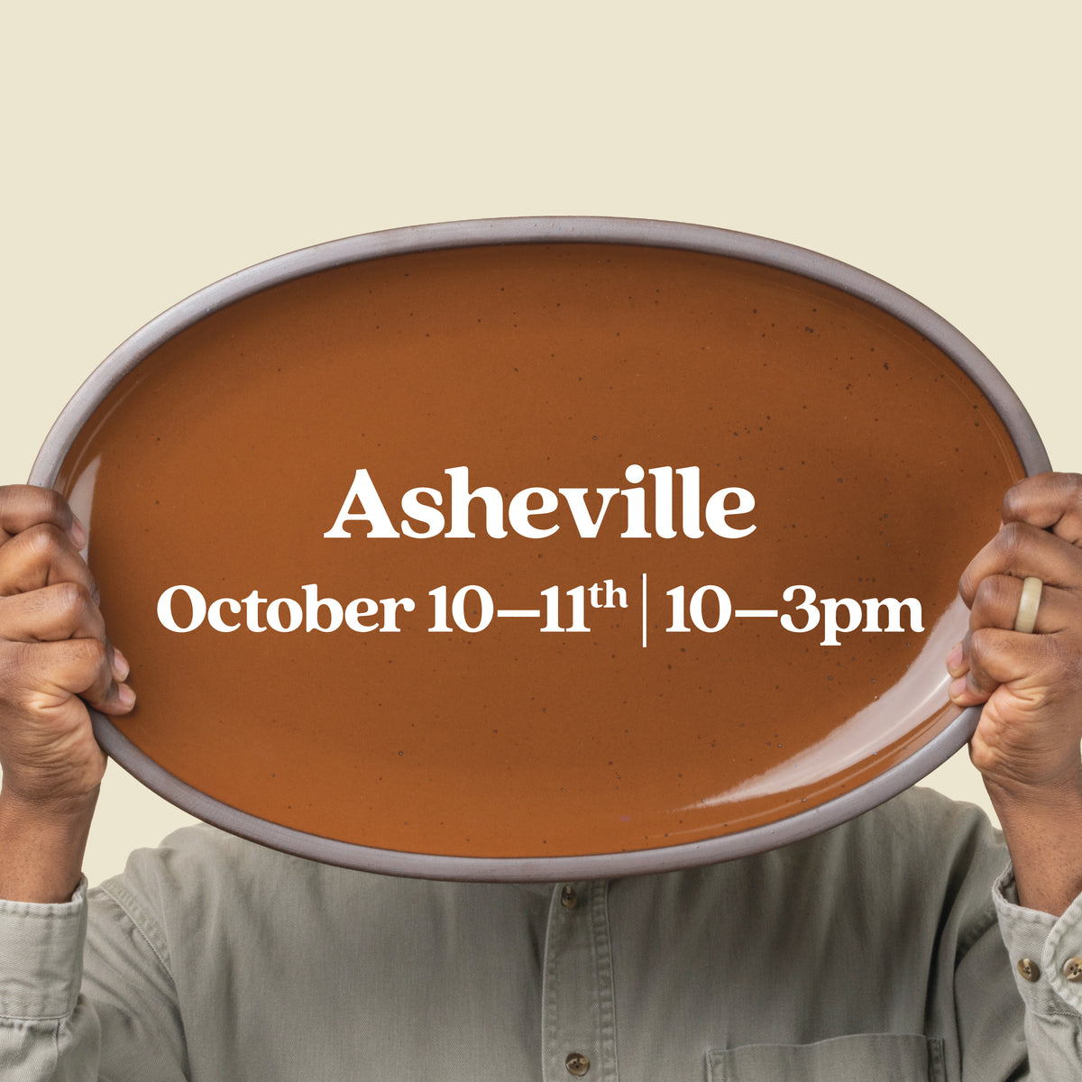 A person holds up a large oval platter in a glossy caramel color with text that reads, 'Asheville October 10-11th, 10-3pm'