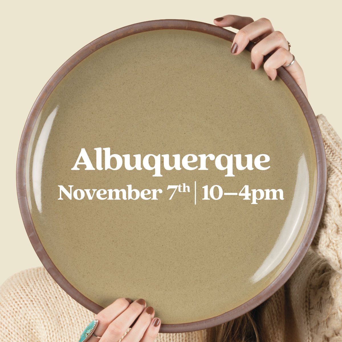 A person holding a large round ceramic platter in front of their face, with white text on the plate reading 'Albuquerque November 7th | 10-4pm'. 
