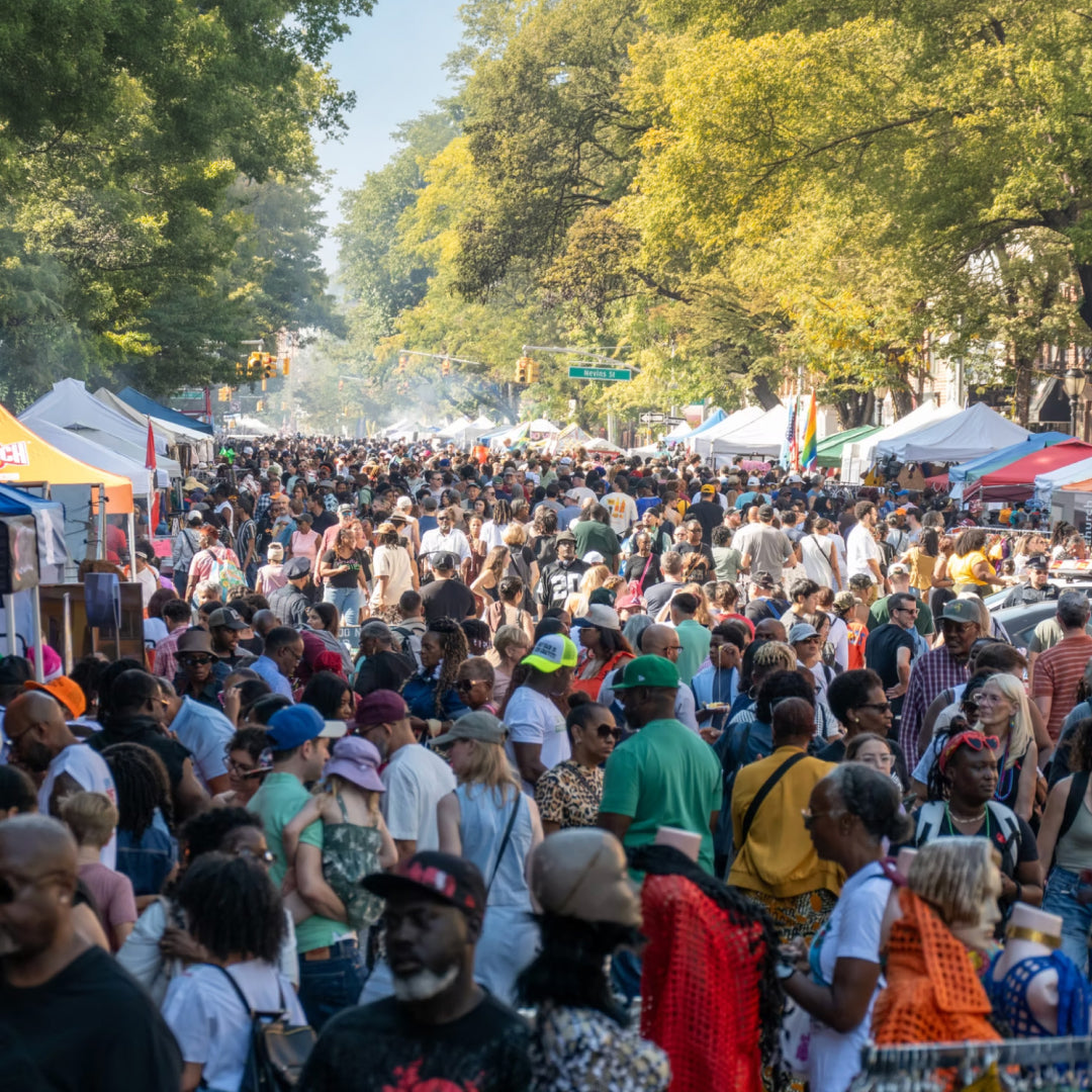 A street in New York filled with people and tents with vendors.