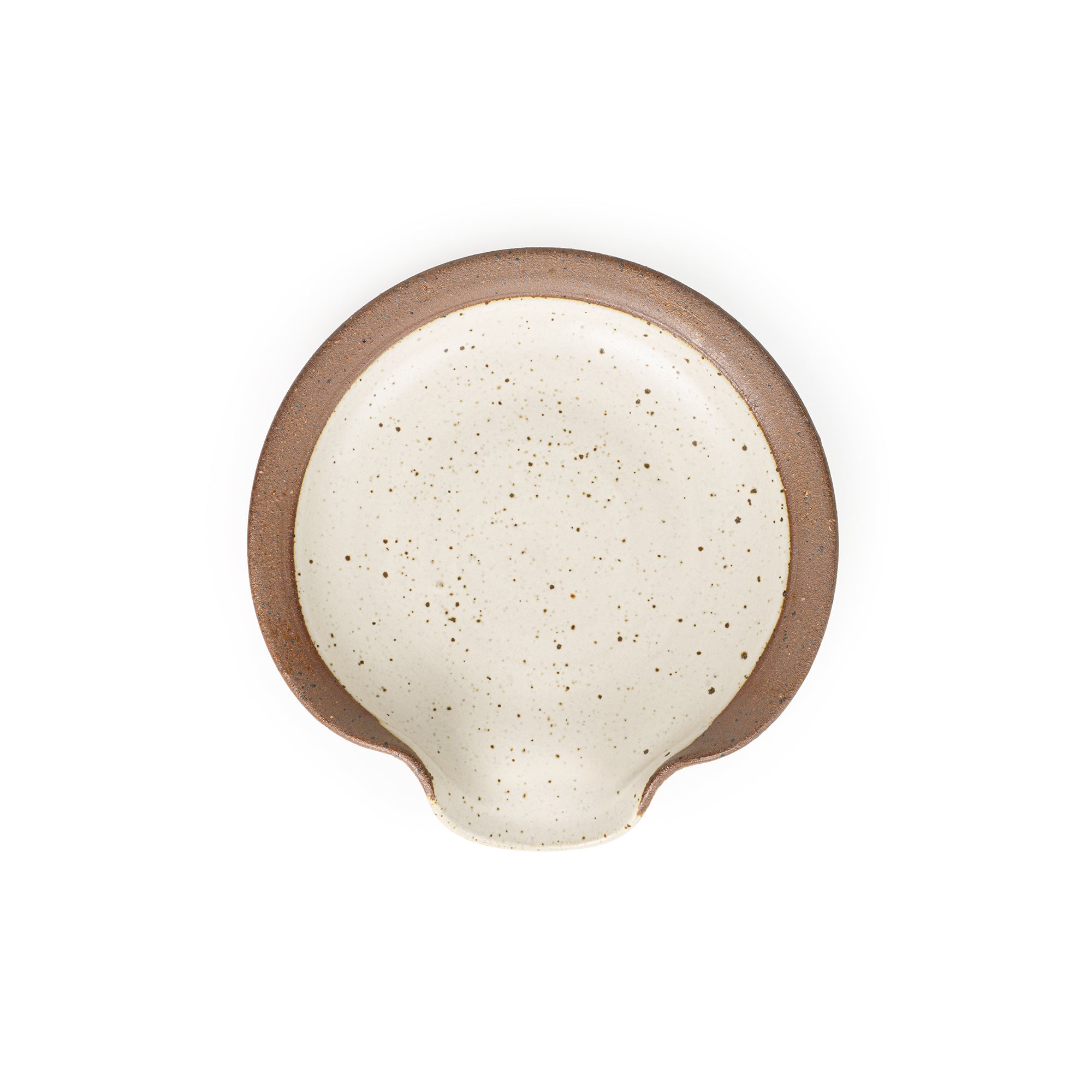 A circular ceramic spoon rest in a warm off-white color featuring iron speckles and unglazed ridge rim