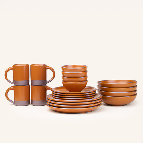 A 20-piece set of ceramic tableware, including mugs, bowls, and plates in an earthy orange color.