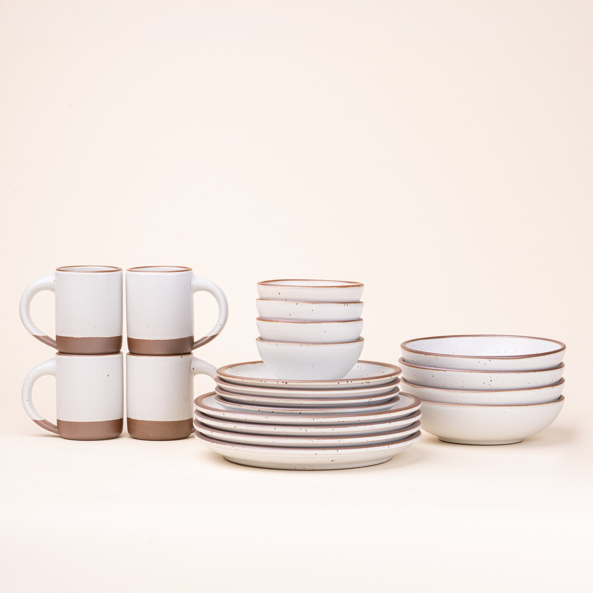 A 20-piece set of ceramic tableware, including mugs, bowls, and plates in a cool white color.