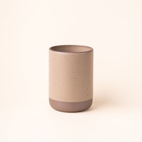 A cylindrical ceramic utensil crock and an unglazed base, in a pale warm brown color.