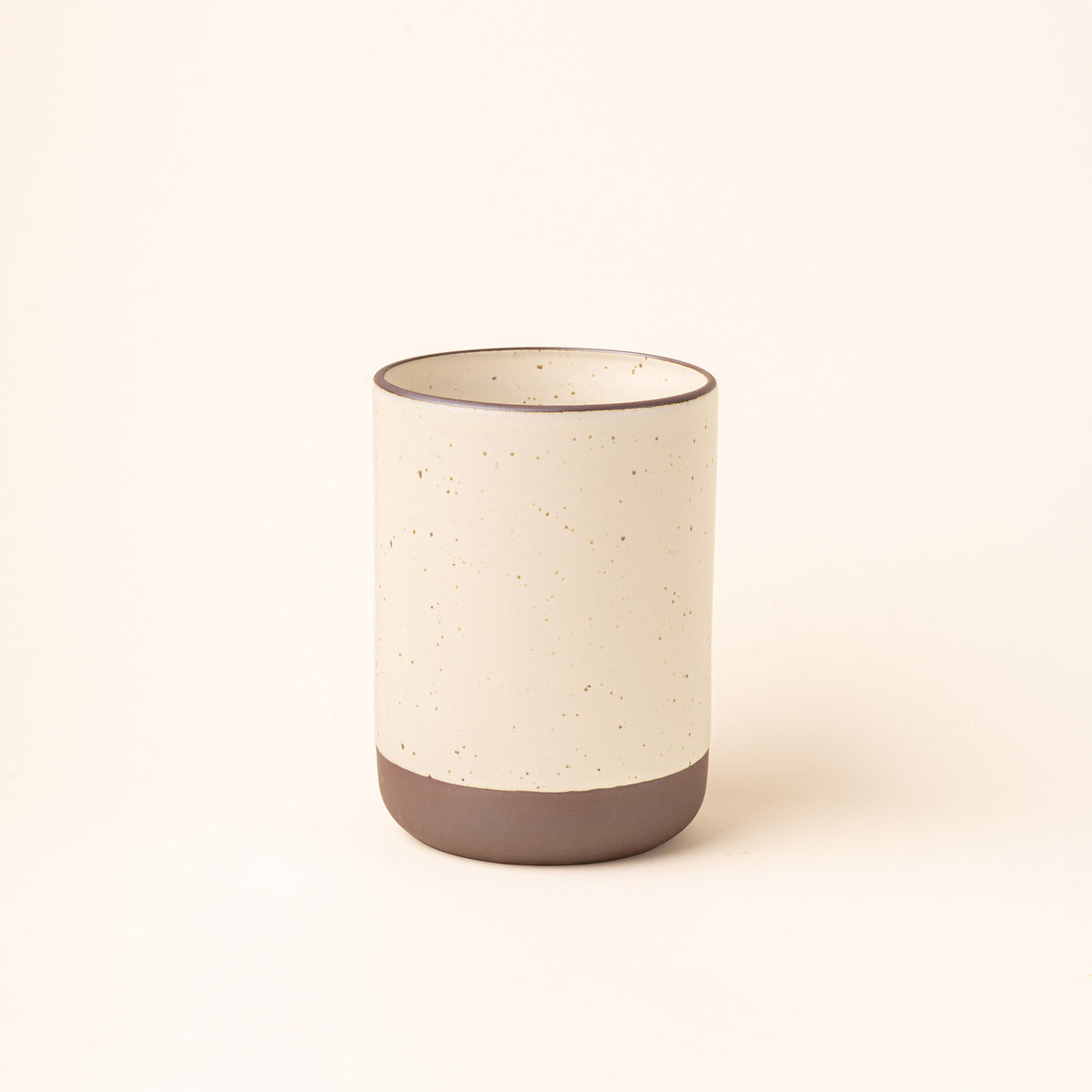 A cylindrical ceramic utensil crock and an unglazed base, in a warm off-white color.