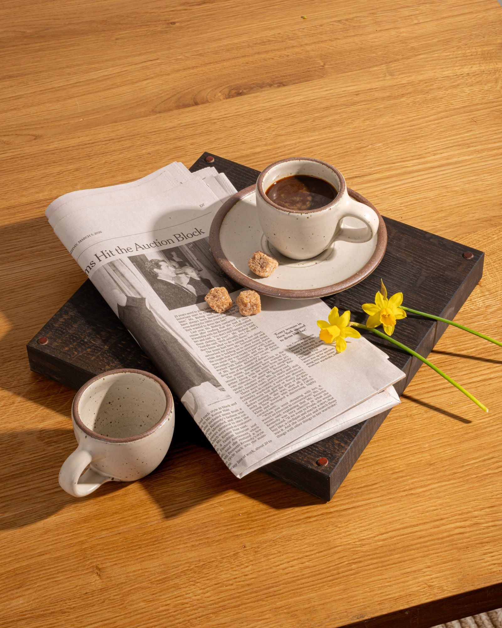 Two espresso cups of coffee on a newspaper with a wooden surface