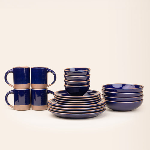 A 20-piece set of ceramic tableware, including mugs, bowls, and plates in a glossy dark blue color.