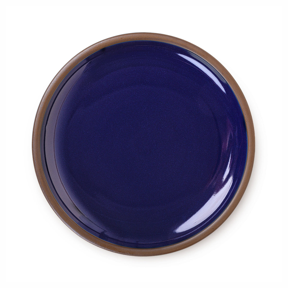 A large ceramic platter in a glossy dark blue color featuring iron speckles and an unglazed rim.