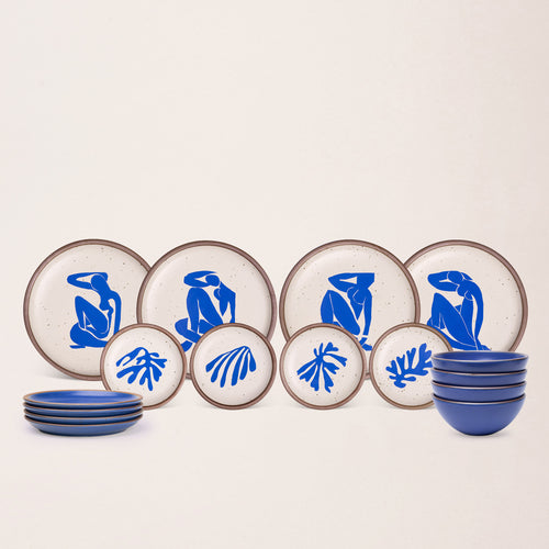 A ceramic dinnerware set arranged on a plain light background, including round plates and bowls in blue and cream with artwork by Henri Matisse featured on the plates.