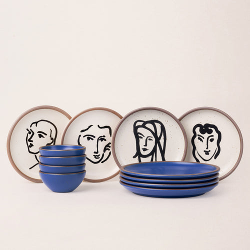 A ceramic dinnerware set arranged on a plain light background, including round plates and bowls in blue, black and cream with artwork by Henri Matisse featured on the plates.