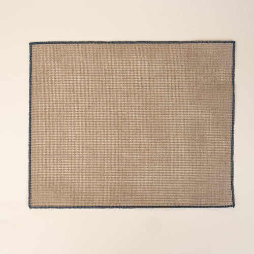 Textured woven placemat in a natural neutral color with a navy border