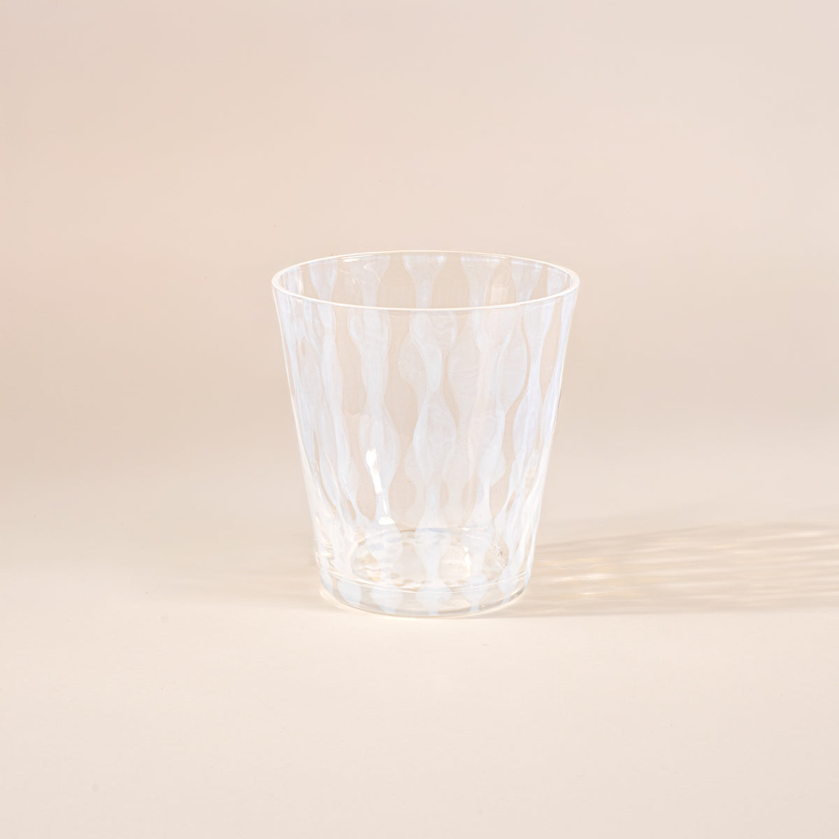 A short clear glass with a delicate vertical wave pattern