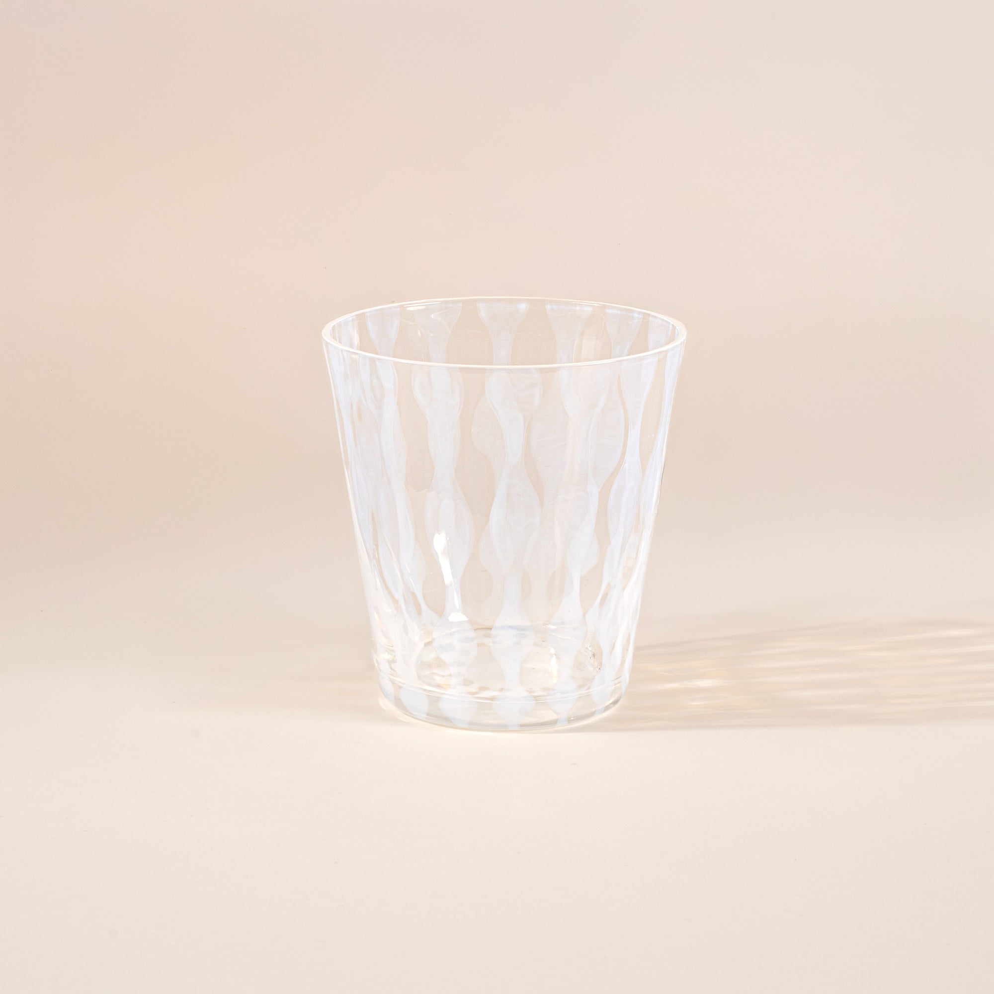 A short clear glass with a delicate vertical wave pattern
