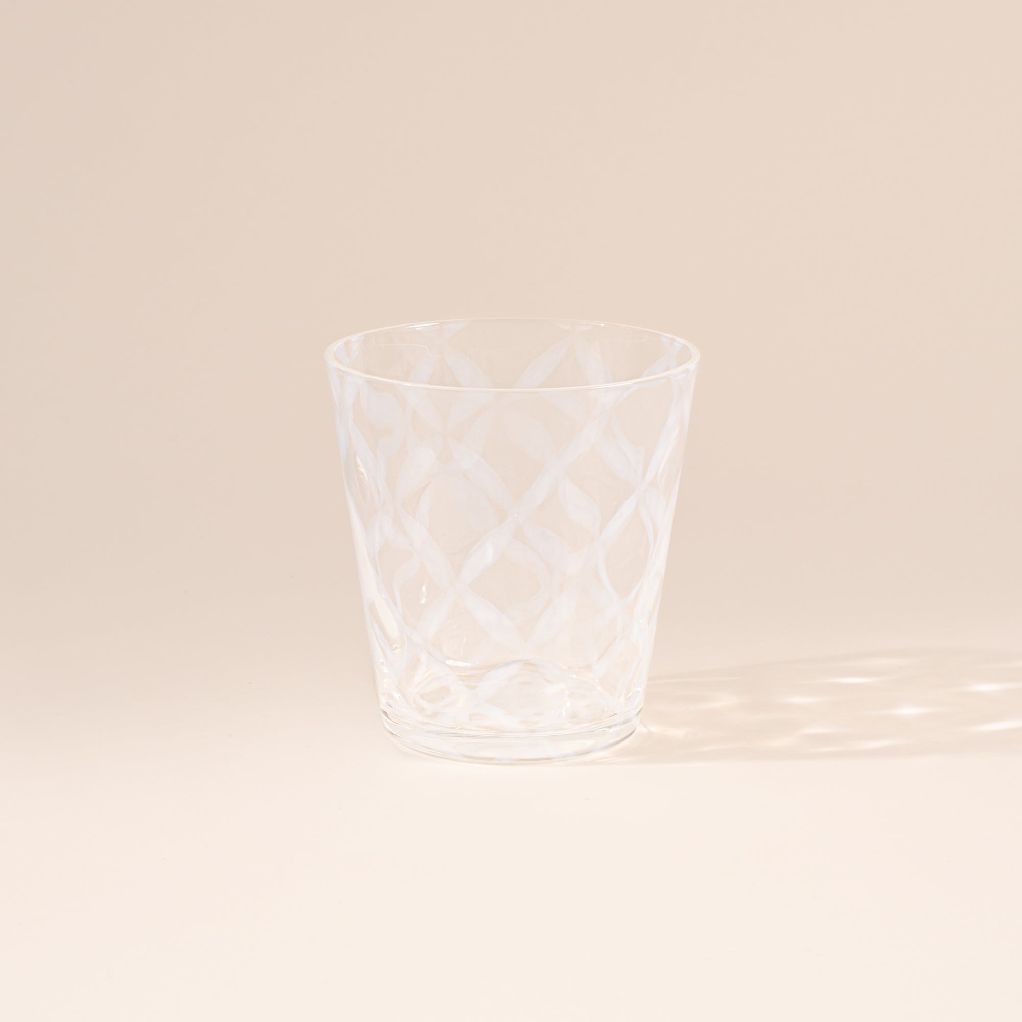 A short clear glass with a delicate grid pattern