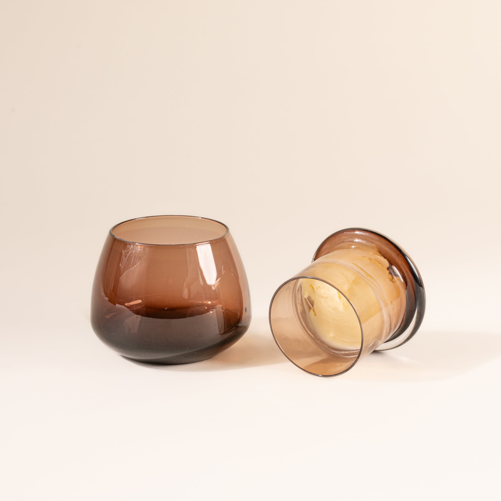 The top of the walnut clear butter keeper filled with butter, resting to the right of the rounded base.