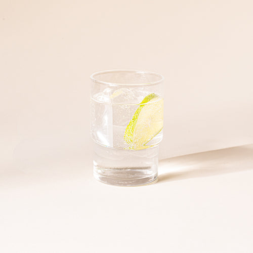 Clear cylindrical glass with a wider top half with a narrower bottom half, filled with a drink.